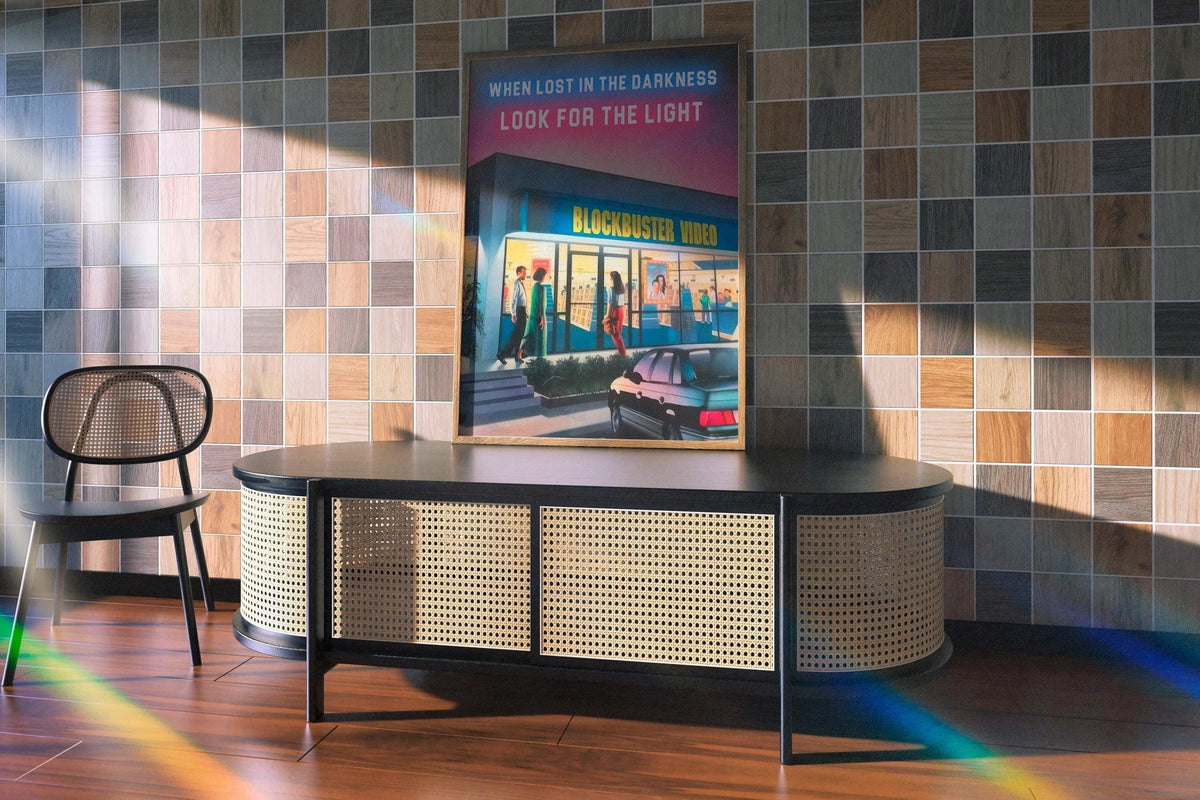 Oak framed 90s video store poster on a checkered tile wall above a cane sideboard